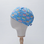 Blue medical humor scrub cap with colorful suture-themed patches displayed on mannequin head