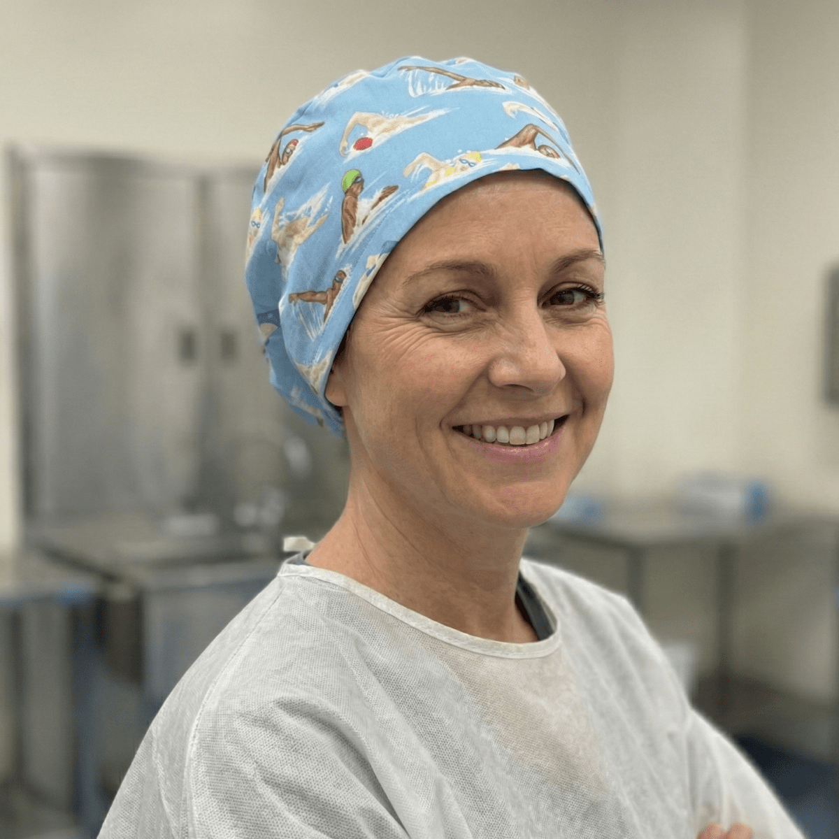 Blue swimmers pattern scrub cap shown on smiling healthcare worker in clinical setting