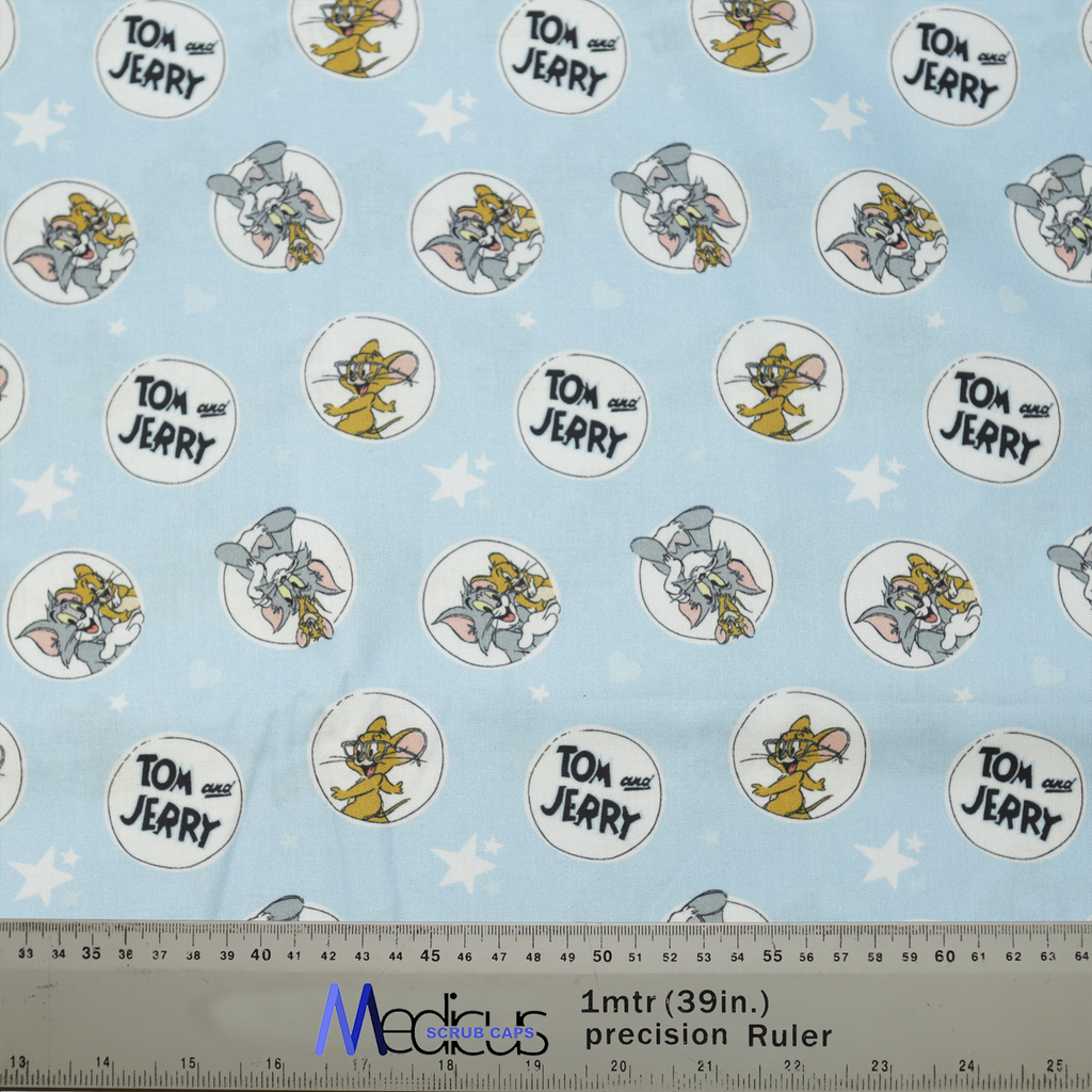 The Medicus Scrub Caps Tom And Jerry Circles On Blue Scrub Cap features light blue fabric with Tom and Jerry patterns, stars, and a ruler for scale.