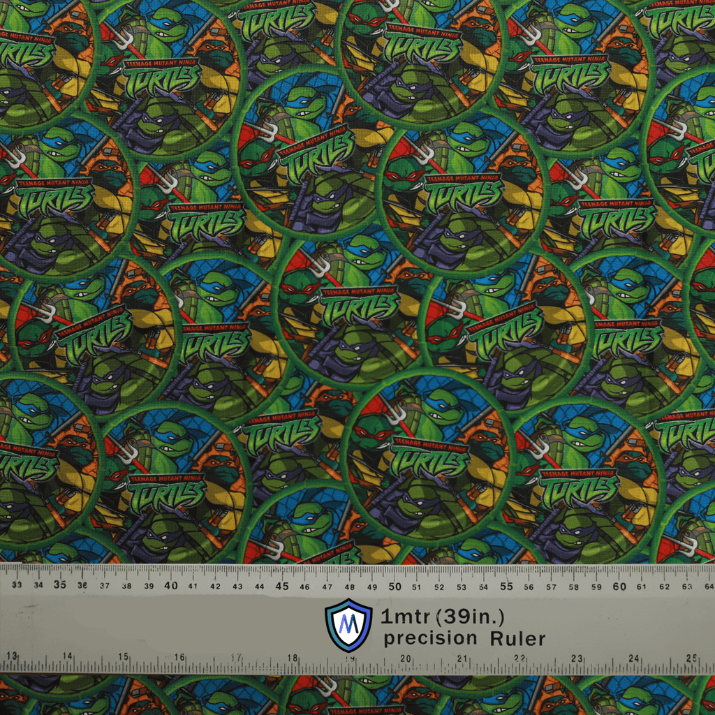 Fabric sample for Medicus Scrub Caps featuring Teenage Mutant Ninja Turtles in bubble print, with a ruler for scale.
