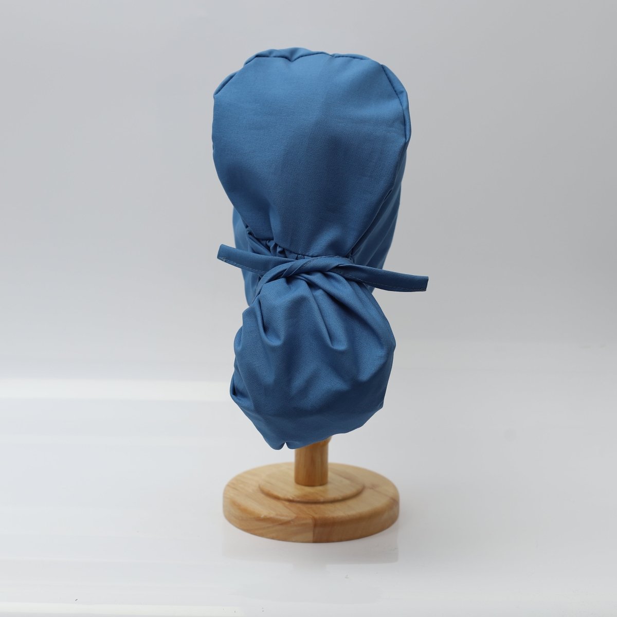 The Pony Scrub Cap in blue, displayed on a mannequin head, showcasing the tied back design for secure fit and comfort.