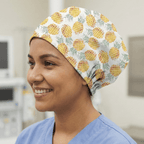 White scrub cap with bright yellow pineapple pattern and green tropical leaves