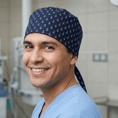 Navy blue anchor pattern scrub cap with tie-back worn by smiling healthcare professional