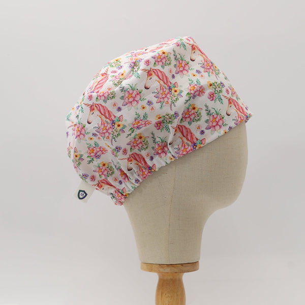 Side view of white custom scrub cap featuring pink unicorns and colorful floral prints. Handmade unicorn floral scrub cap by Medicus Caps in a bouffant style, suitable for medical professionals or long hair.