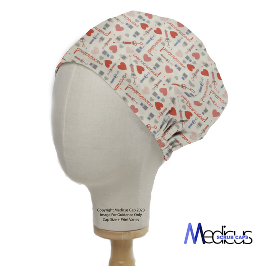 A mannequin head displays a Medicus Scrub Caps Covid Vaccine Love Scrub Cap with medical-themed prints, featuring syringes, hearts, and "vaccinated" text, celebrating healthcare professionals.