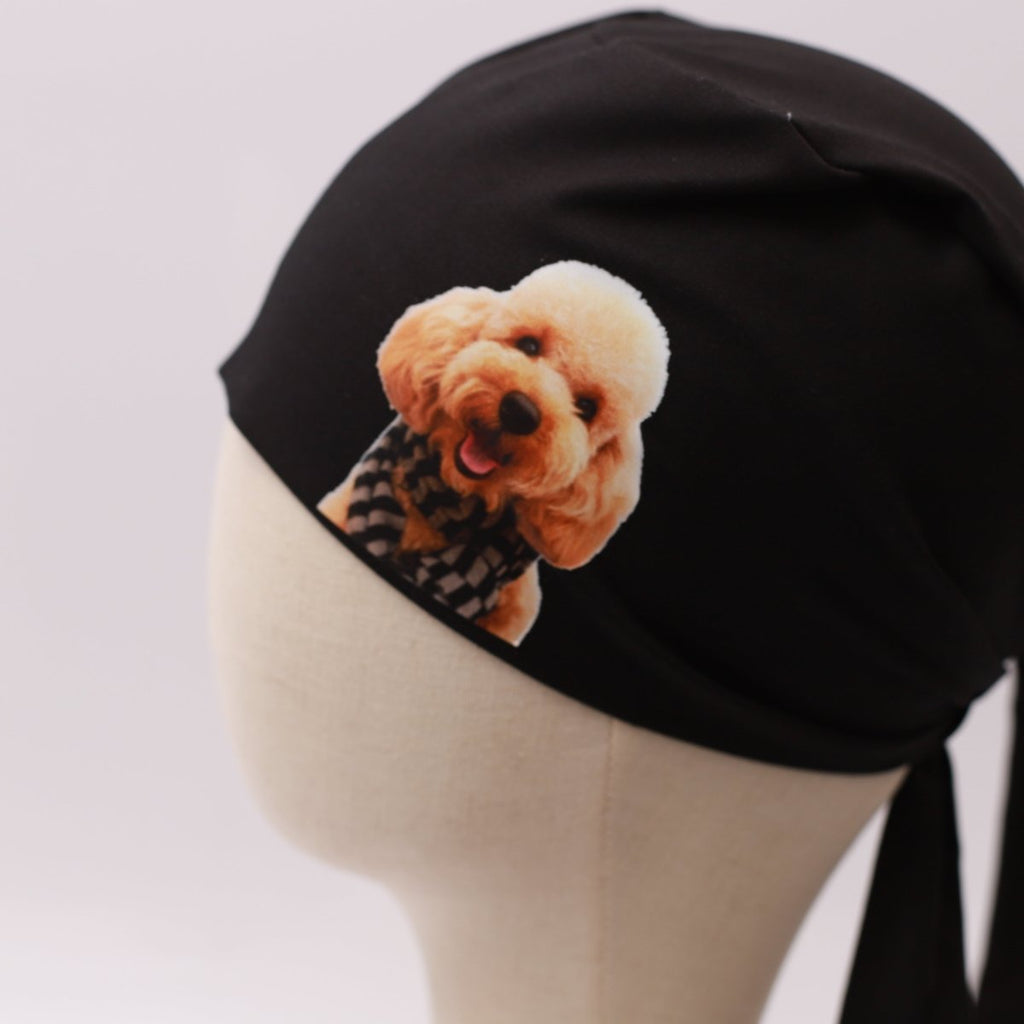 Black Medicus scrub cap with a vinyl sticker of a smiling poodle wearing a checkered scarf. Custom design by @scrub-caps-with-vinyl-stickers.