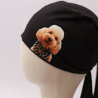 Black Medicus scrub cap with a vinyl sticker of a smiling poodle wearing a checkered scarf. Custom design by @scrub-caps-with-vinyl-stickers.