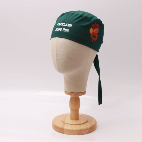 Green Medicus scrub cap with "Parkland Surg Onc" text and an organ illustration, displayed on a mannequin. Custom design from @scrub-caps-with-vinyl-stickers.