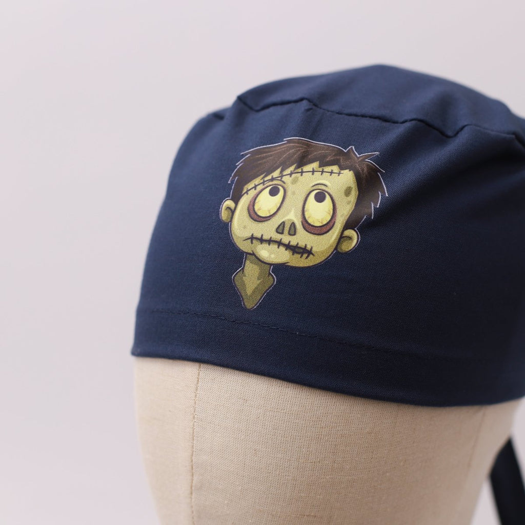 Navy blue Medicus scrub cap with a vinyl sticker of a cartoon zombie face. Part of the "scrub-caps-with-vinyl-stickers" collection.