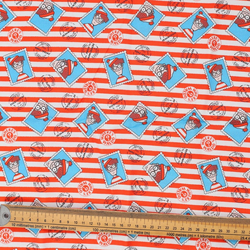 Close-up of Where's Waldo fabric with red-and-white stripes, turquoise framed Waldo illustrations and ruler for scale.