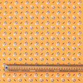 Patterned fabric with cartoon characters on a yellow background, ruler for scale.