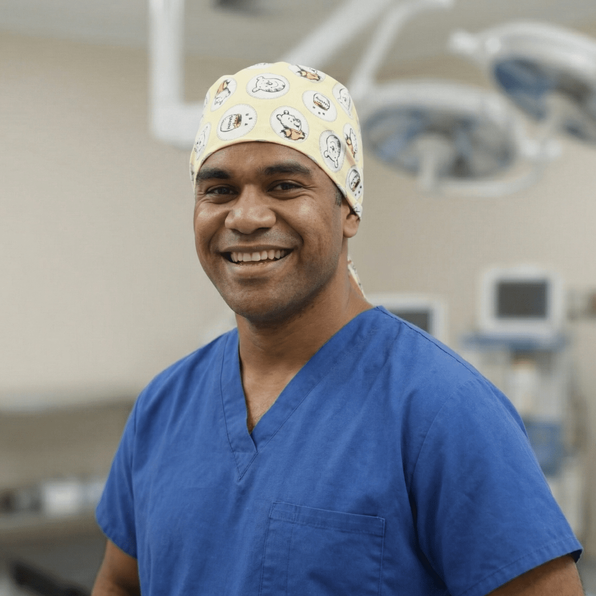 Healthcare professional wearing Winnie the Pooh honey pots scrub cap in operating room setting