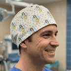 Wonder Woman logo pattern scrub cap with yellow and blue superhero design on cream background