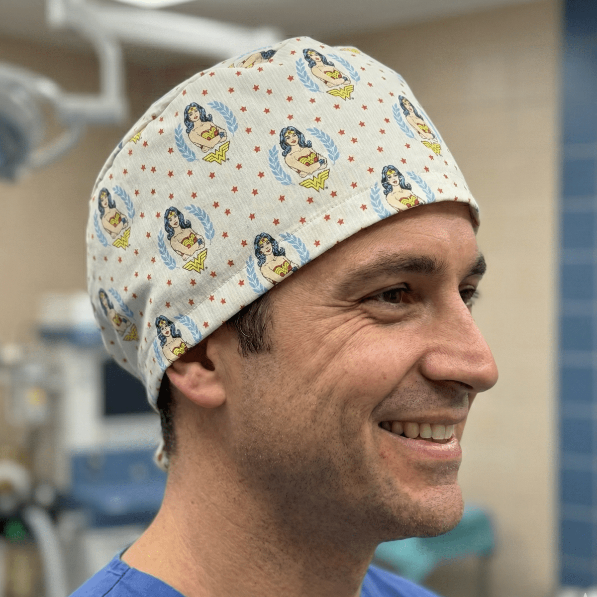 Wonder Woman logo pattern scrub cap with yellow and blue superhero design on cream background
