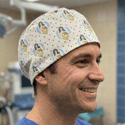 Wonder Woman logo pattern scrub cap with yellow and blue superhero design on cream background