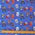 Close-up of blue scrub cap fabric featuring colorful wrestling masks with ruler for scale.