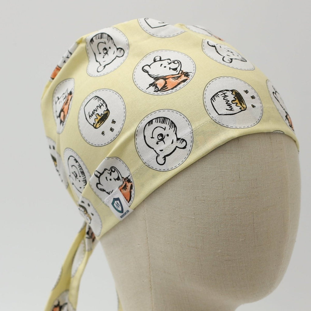 Yellow custom scrub cap featuring cartoon faces design, handmade by Medicus Caps