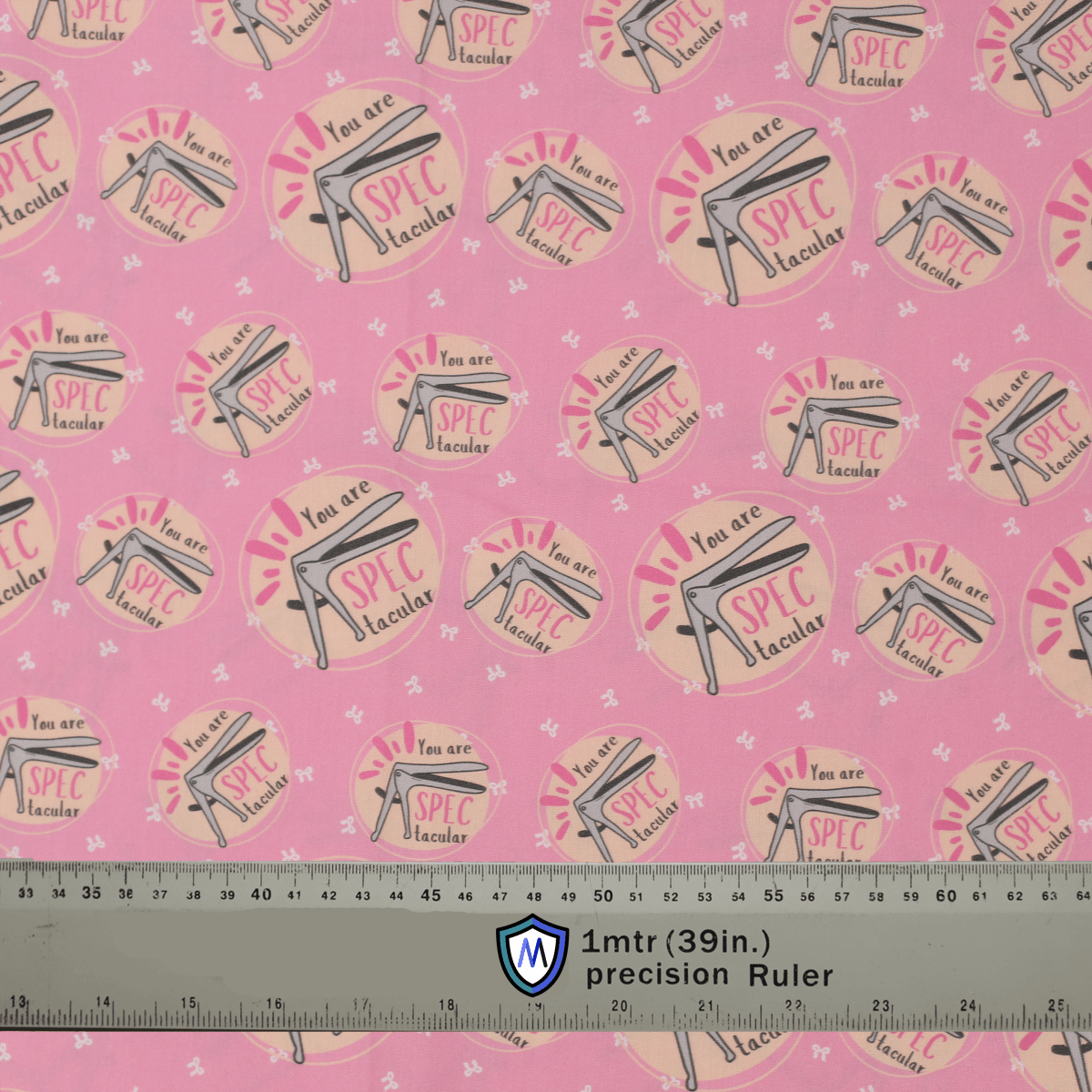 Pink Medicus Scrub Caps fabric with a speculum pattern and "You are SPECtacular" text, alongside a ruler for scale.