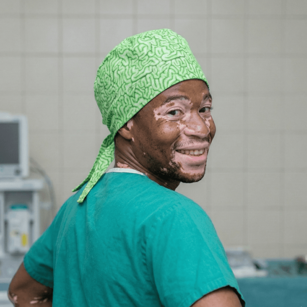 Healthcare worker wearing green zombie brain pattern scrub cap, side profile view in medical setting