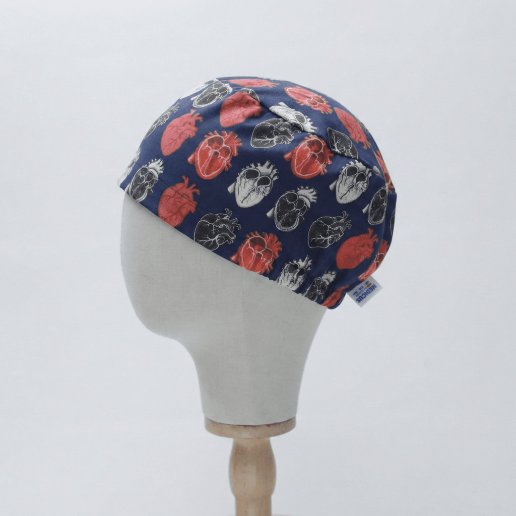 Navy blue surgical cap with anatomical heart pattern on a mannequin head against a light gray background