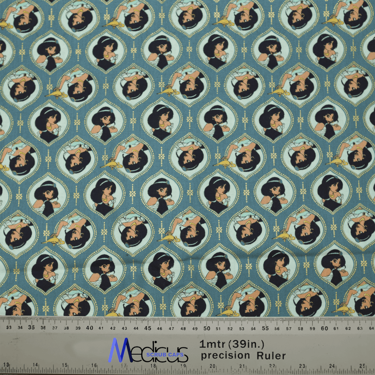 The Aladdin Jasmine Heads Theatre Cap by Medicus Scrub Caps showcases stylized portraits of a character like Jasmine in various poses. The teal and blue design, featuring decorative elements, is ideal for healthcare professionals. A ruler at the bottom provides measurements.
