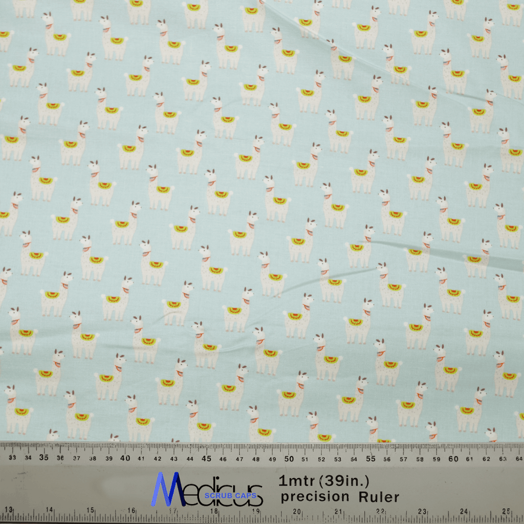 The whimsical Alpaca / Llama Party Blue Scrub Cap by Medicus Scrub Caps features cartoon llamas with saddles on a light blue fabric. Its perfect for medical attire, and a ruler at the bottom offers precise measurements in inches and centimeters, highlighting its detailed design.