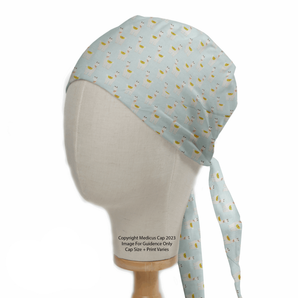 A mannequin head displays a light blue surgical cap with a fun pineapple pattern, made from eco-friendly materials. Resembling the Medicus Scrub Caps Alpaca/Llama Party Blue Scrub Cap, it has long ties and advisory text, with sizes and prints that may vary.