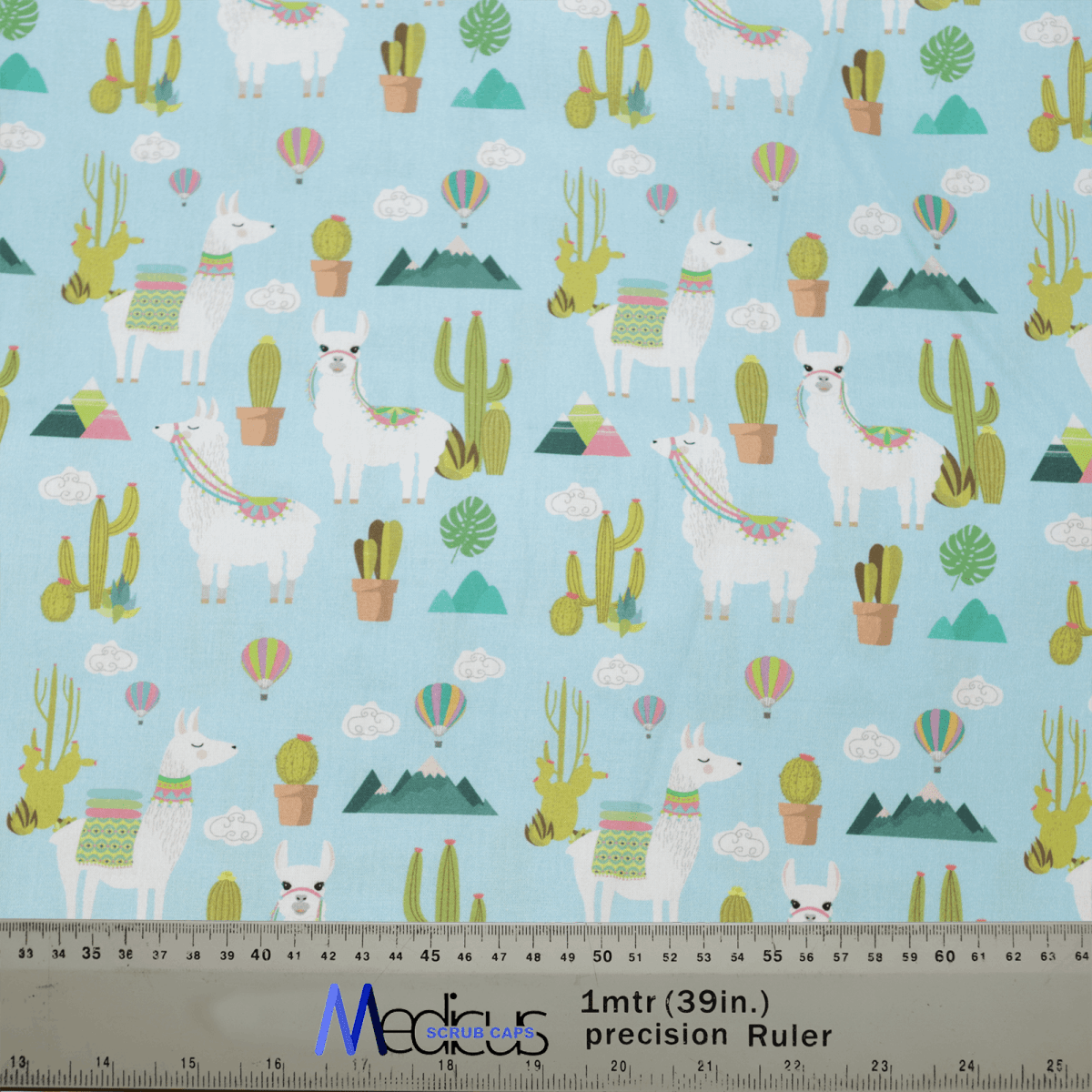 Medicus Scrub Caps Alpaca Mountain Blue Theatre Cap showcases a whimsical pattern of white llamas with colorful blankets amid cacti, potted plants, and hot air balloons on a light blue background, combining ultimate comfort and a scale ruler.