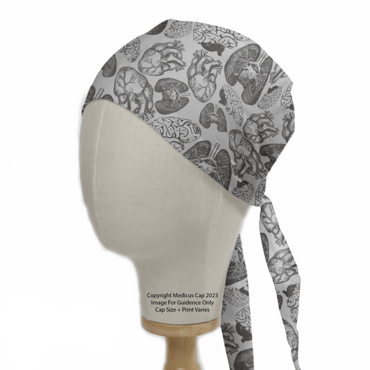 The mannequin head displays Medicus Scrub Caps Anatomy Heart Lungs Brains design, a gray surgical cap adorned with intricate black anatomical prints of human organs like the brain and heart. This reusable scrub cap ties at the back, offering an educational flair for healthcare professionals.