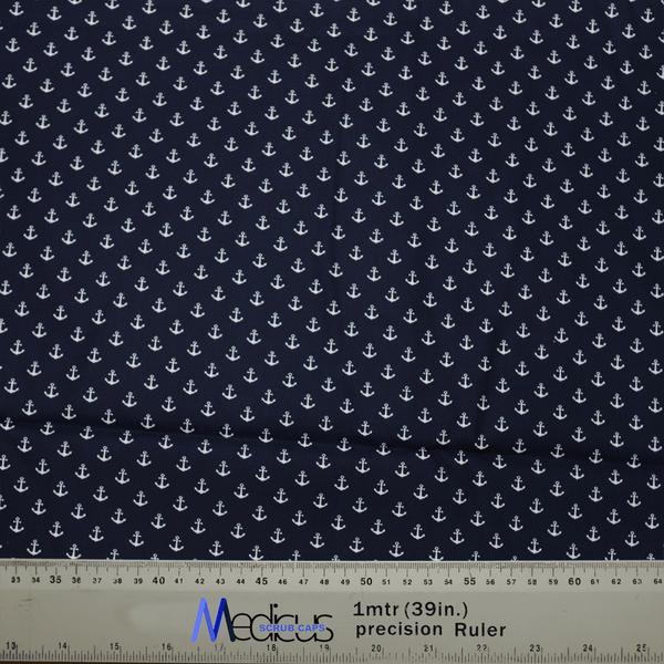 The Anchors On Navy Scrub Cap by Medicus Scrub Caps showcases a pattern of white anchors on dark blue fabric, designed to be eco-friendly and reusable. A ruler with centimeters and inches is visible below, partly revealing the Medicus label.