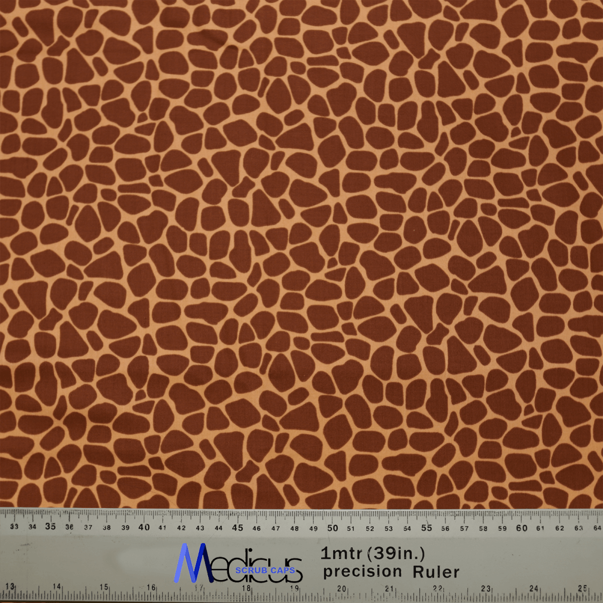 The Medicus Scrub Caps Animal Print Giraffe Scrub Cap, ideal for healthcare workers, showcases a chic giraffe pattern in brown and beige. It includes a ruler at the bottom for measurements in centimeters and inches, with blue and black text highlights.
