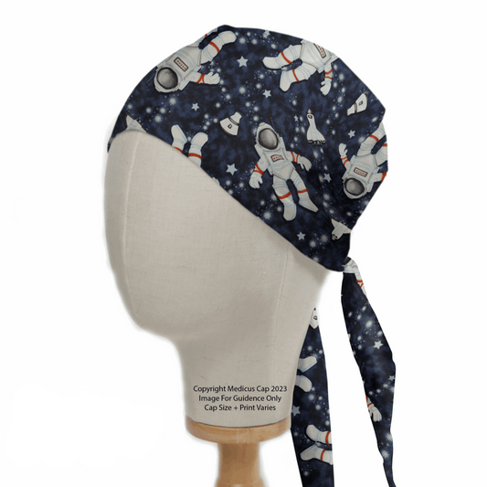 A Medicus Scrub Caps mannequin displays an Astronauts Spaceman Scrub Cap, featuring astronaut and rocket prints on a navy starry background. This reusable cap is complemented by long ties flowing down the back.