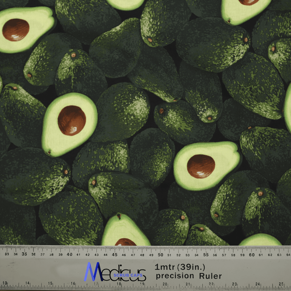 Dark fabric adorned with whole and halved green avocados, perfect for crafting the Avocados Scrub Cap by Medicus Scrub Caps—a sustainable choice for healthcare professionalism. Features a ruler at the bottom displaying 1m (39in.) with side markings.