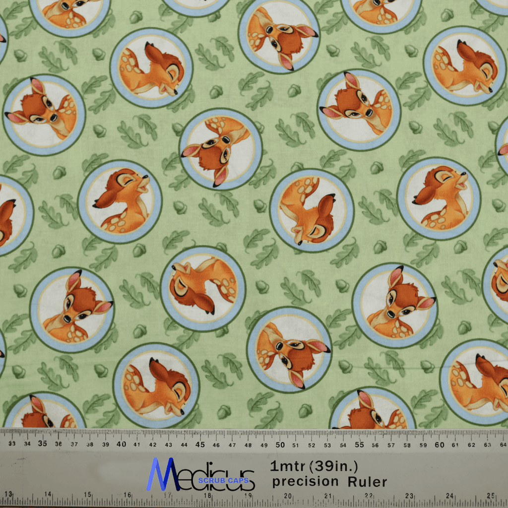 The Bambi Laughing On Green Scrub Cap by Medicus Scrub Caps features cartoon deer heads in circular frames, whimsically inspired by Bambi, with occasional footprints and plants for added charm. A ruler at the bottom shows dimensions in inches and meters, perfect for an eco-friendly design.