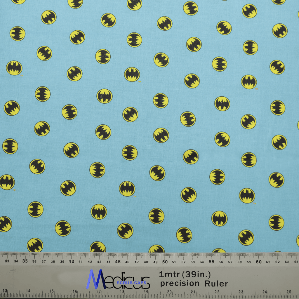 The Batman Signal On Blue Scrub Cap by Medicus Scrub Caps boasts a light blue fabric with small yellow and black bat symbols, similar to the Batman Signal. It includes a ruler for accurate measurements in inches and centimeters for perfect scaling.
