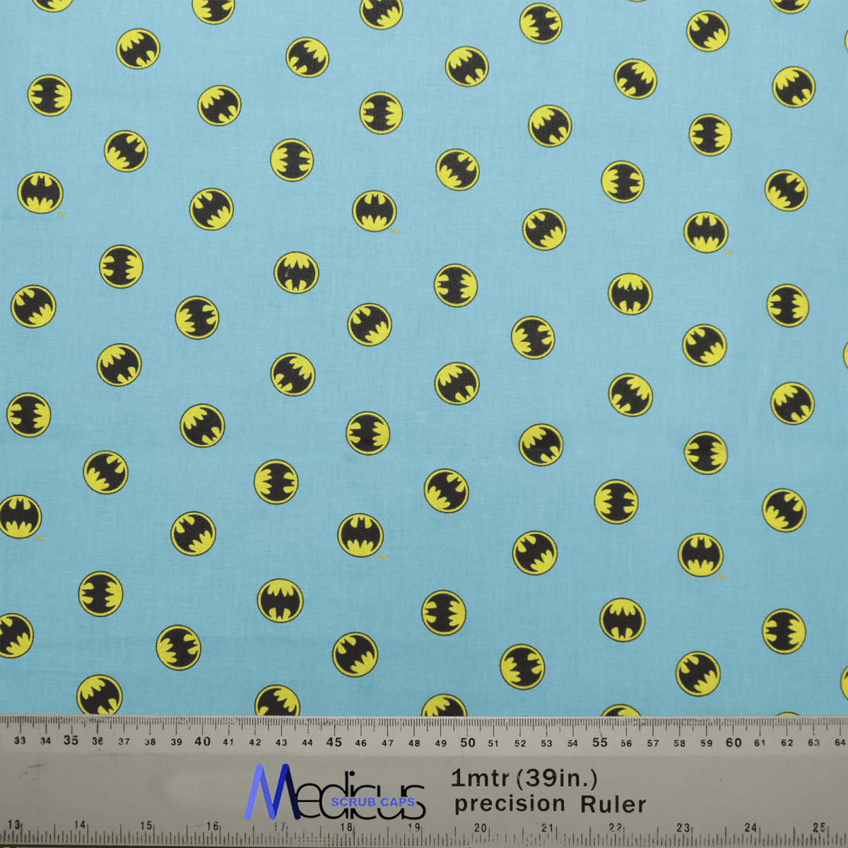 The Batman Signal On Blue Scrub Cap by Medicus Scrub Caps boasts a light blue fabric with small yellow and black bat symbols, similar to the Batman Signal. It includes a ruler for accurate measurements in inches and centimeters for perfect scaling.