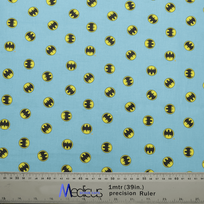 The Batman Signal On Blue Scrub Cap by Medicus Scrub Caps boasts a light blue fabric with small yellow and black bat symbols, similar to the Batman Signal. It includes a ruler for accurate measurements in inches and centimeters for perfect scaling.