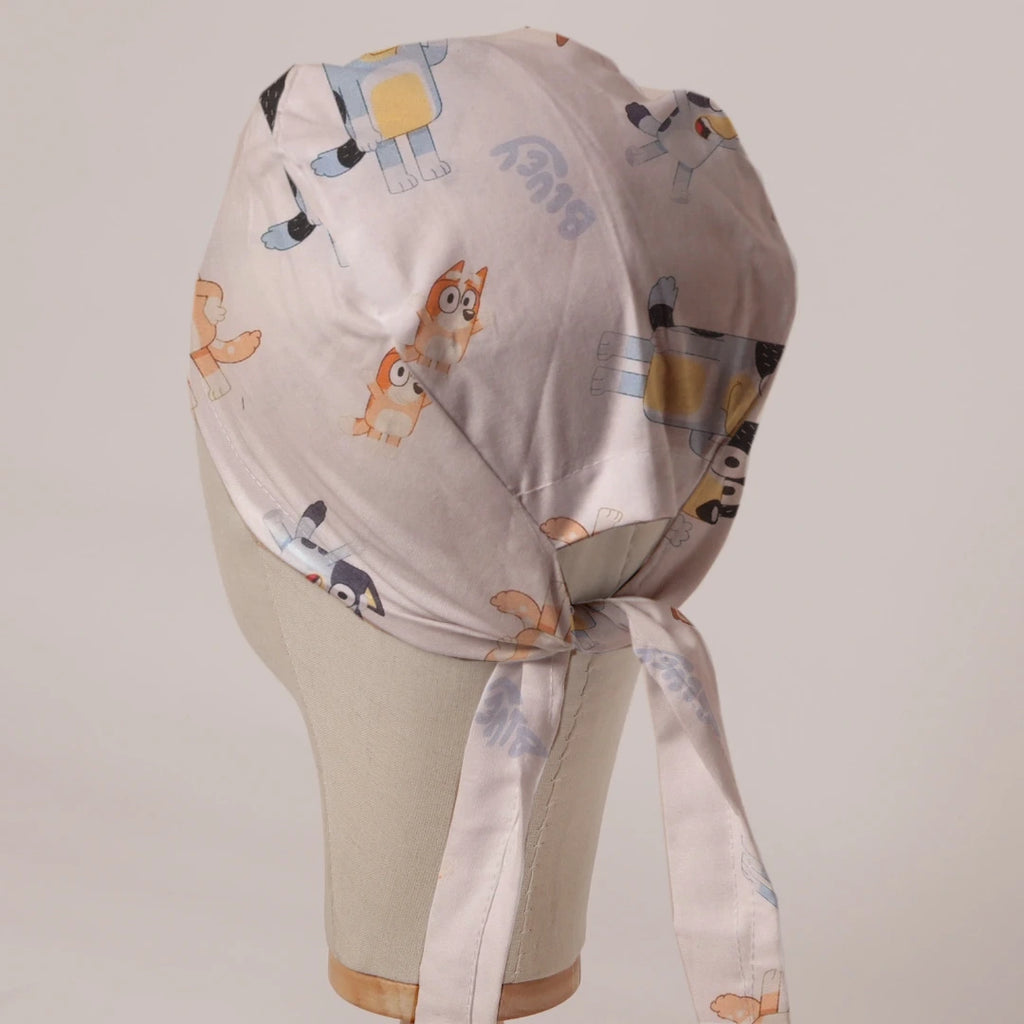 Bluey and Bingo Tossed on White fabric scrub cap in Bandana tie-back style on mannequin head, back view with ties