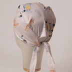 Bluey and Bingo Tossed on White fabric scrub cap in Bandana tie-back style on mannequin head, back view with ties