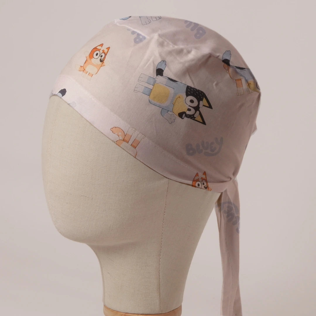 Bluey and Bingo Tossed on White fabric scrub cap in Bandana tie-back style: Bluey and Bingo tossed on white