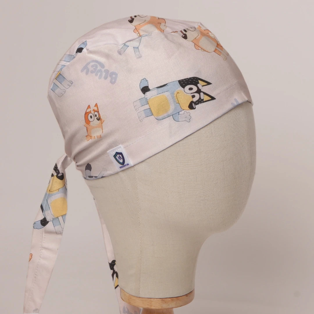Bluey and Bingo Tossed on White fabric scrub cap in Bandana tie-back style on mannequin head, front right view with the