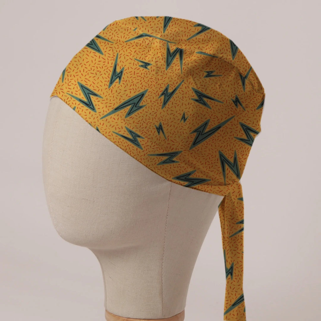 Electric Bolts On Yellow scrub cap in Bandana tie-back style: teal lightning bolts on speckled mustard yellow