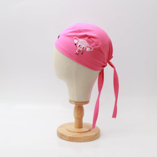 The pink Embroidery - Uterus - Scrub Cap by Medicus Scrub Caps features a cute sheep illustration, custom embroidered on the side. Displayed on a mannequin head with convenient back ties, it is reusable and set against a plain white background.