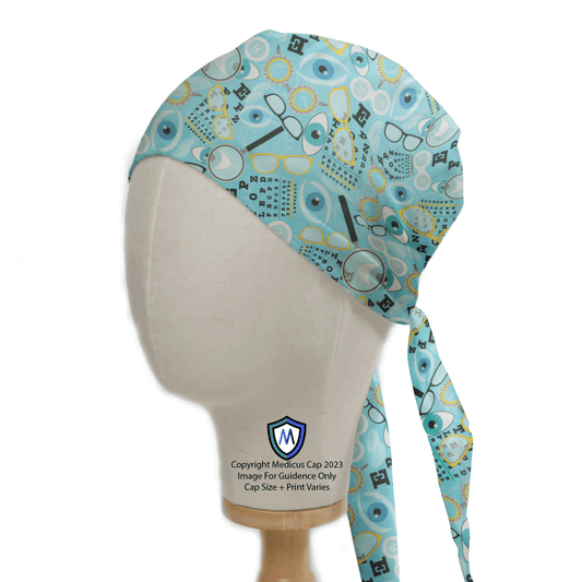 A Medicus Scrub Caps mannequin head models the eco-friendly Eye Doctor Mashup Scrub Cap, featuring glasses, eye charts, and ophthalmology symbols on a light blue background.