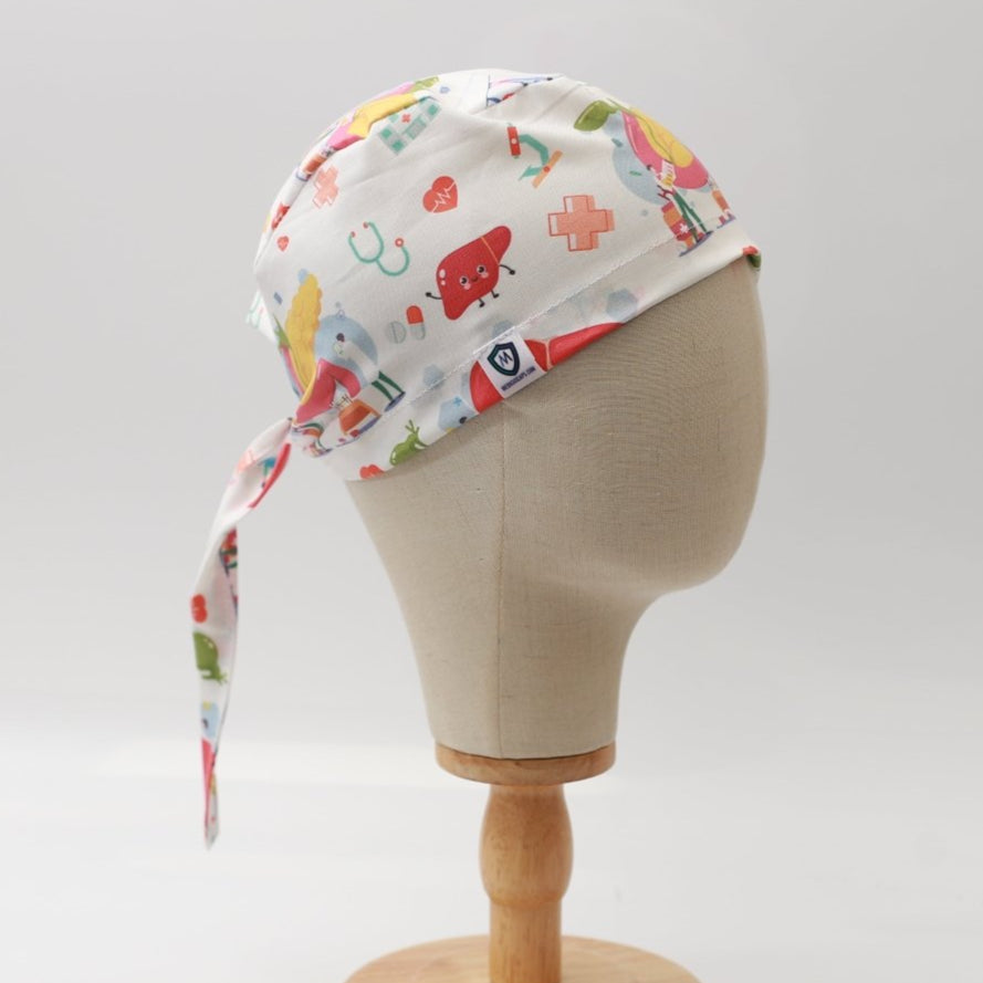 Mannequin head wearing a Medicus Scrub Cap with a medical-themed print featuring organs like the liver, gallbladder, and pancreas.