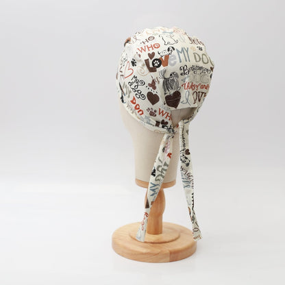 The Medicus Scrub Caps I Love My Dogs scrub cap is ideal for veterinary professionals, showcasing dog-themed prints like dogs, paw prints, bones, and hearts on a mannequin. Featuring phrases such as Woof, My Dog, and Hug, along with long ties at the back.