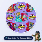 It's Behind You scrub cap print: pantomime characters with anaesthetic machines peeking from behind red curtains on lilac, with a Pre Order For October 2026 badge