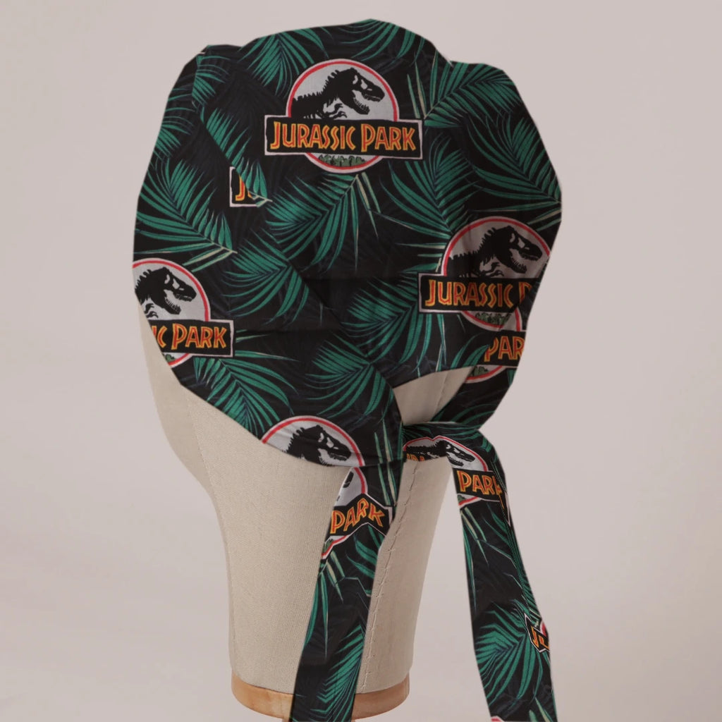Jurassic Park Logo Jungle fabric scrub cap in Bandana tie-back style on mannequin head, back view with ties