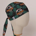 Jurassic Park Logo Jungle fabric scrub cap in Bandana tie-back style on mannequin head, front right view with the Medicus