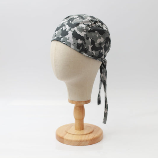 A mannequin head displays a Medicus Scrub Caps Military Camouflage Grey Scrub Cap, blending comfort and style, on a wooden stand against a plain white background.